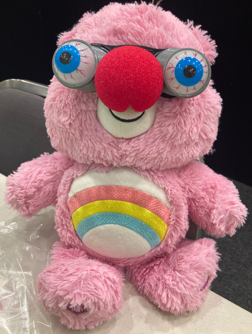 Pink Care bear plushy. Red clown nose and wobbly googly eyes.