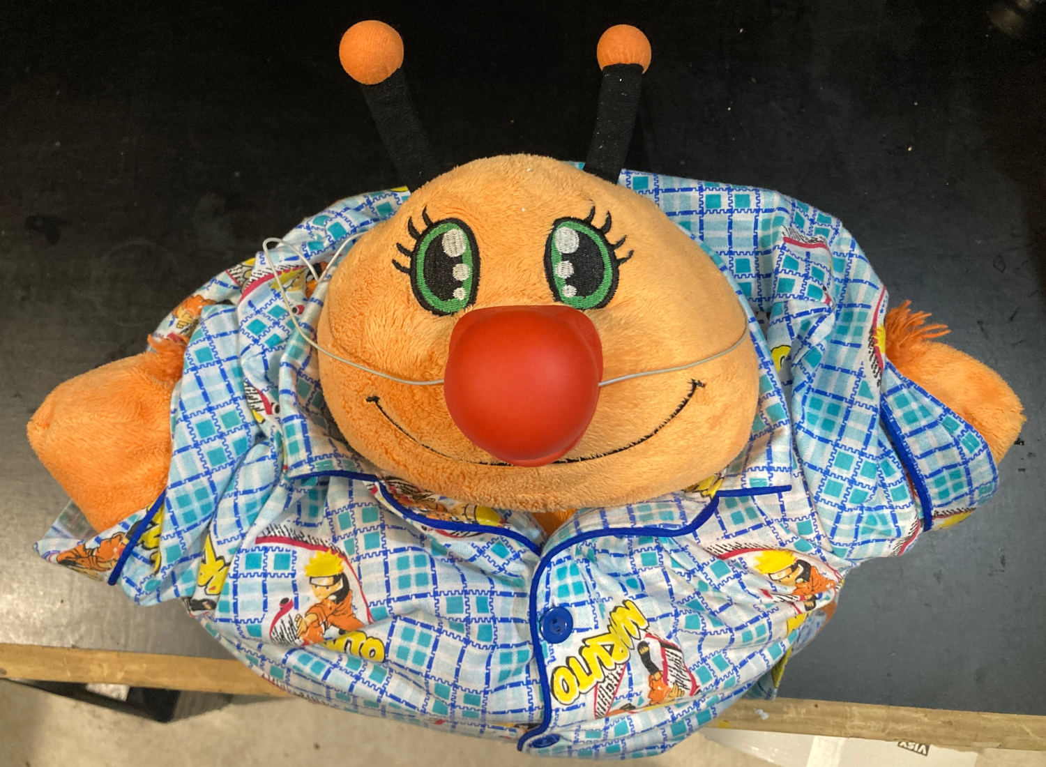 Orange butterfly pillow pet. Red clown nose, wearing blue Naruto pyjamas.