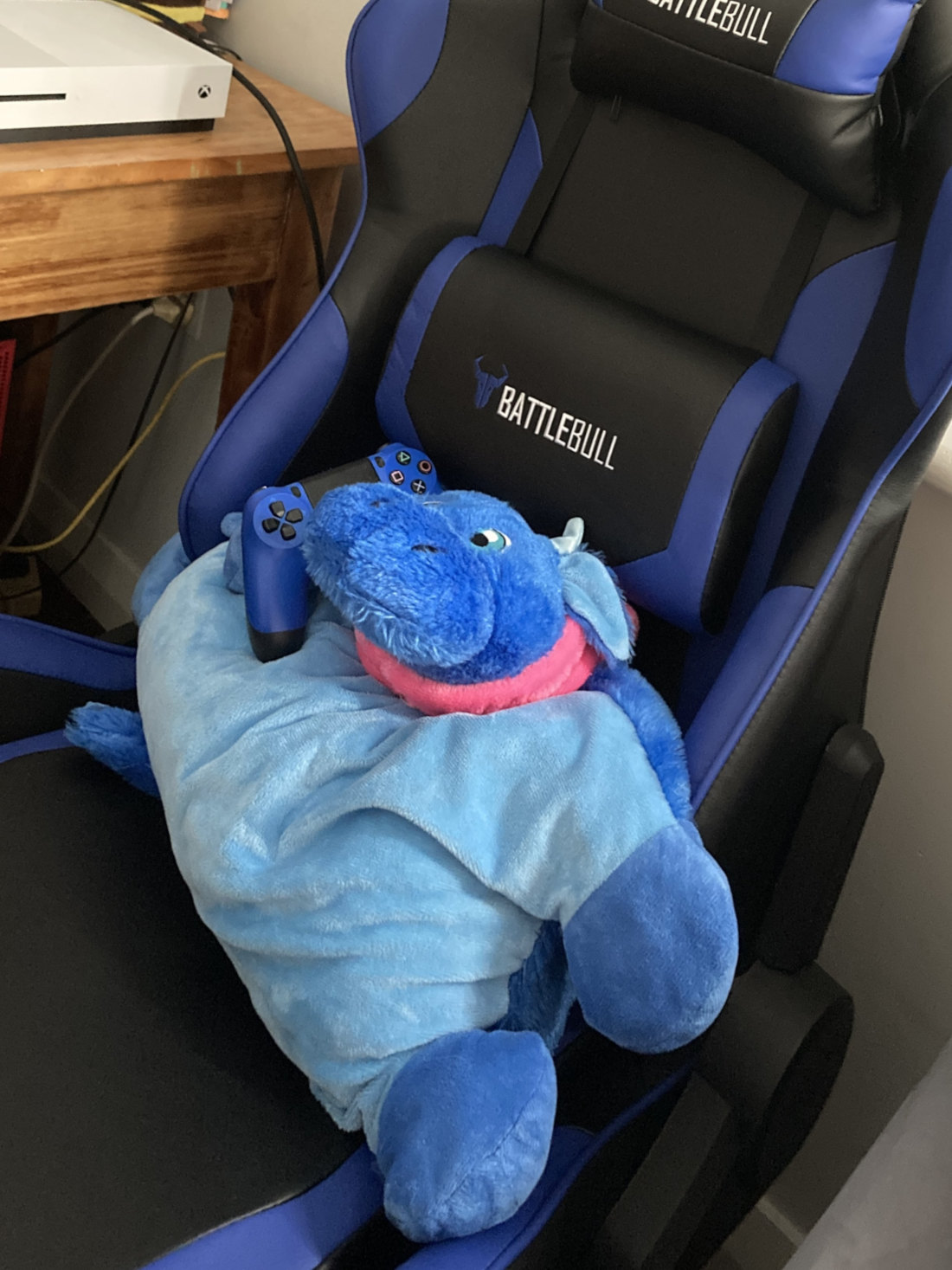 Blue dragon plushy sitting in blue chair holding blue controller
