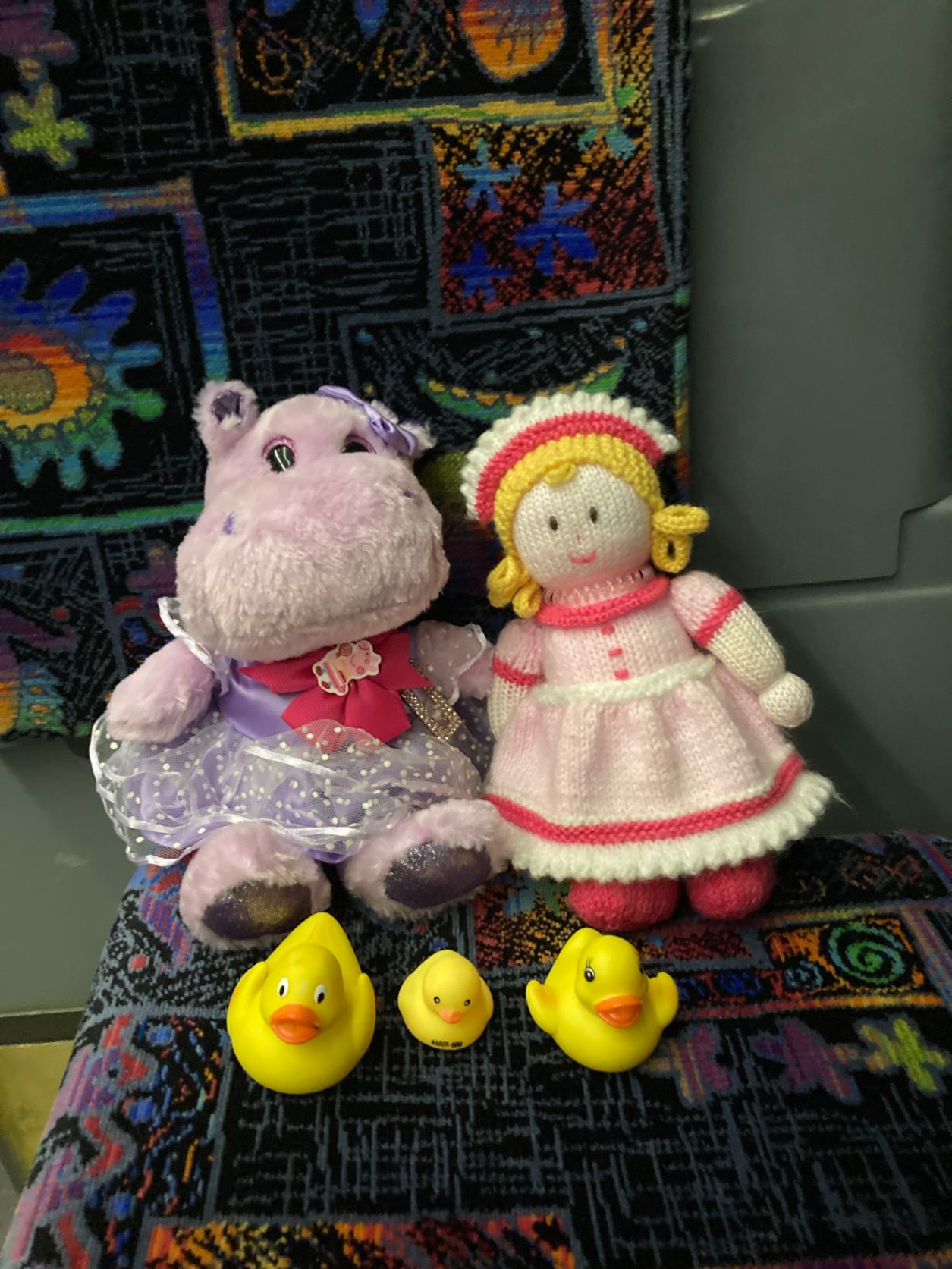 Croche Doll, pink outfit. Purple hippo stuffie all purple. 3 yellow duckies. All on bus seat.