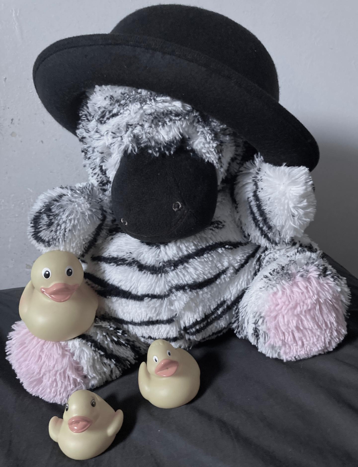 Black Zebra plushy wearing bowler hat. 3 rubber duckies.