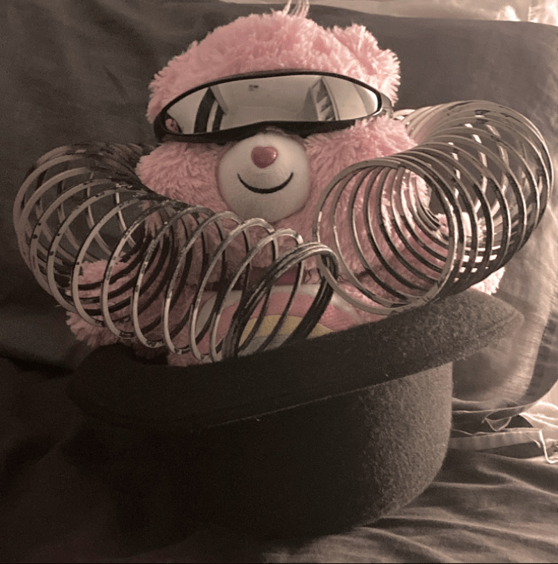 Care Bear plushy, cyclops sunnies, sit in bowler hat, black and white slinky worn around neck