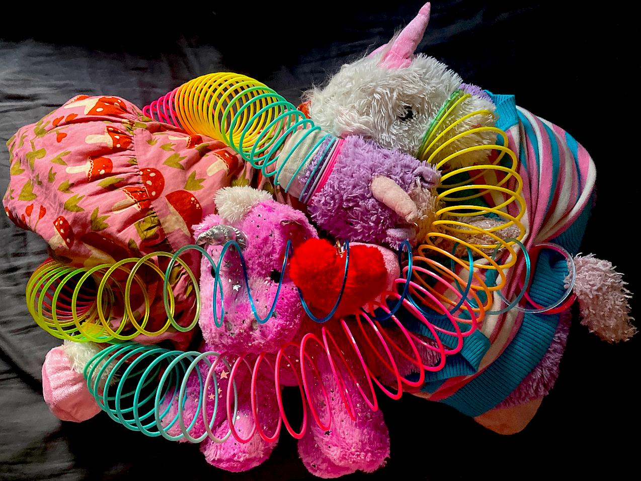 Four unicorn plushies caught in a tangled slinky cuddle puddle.